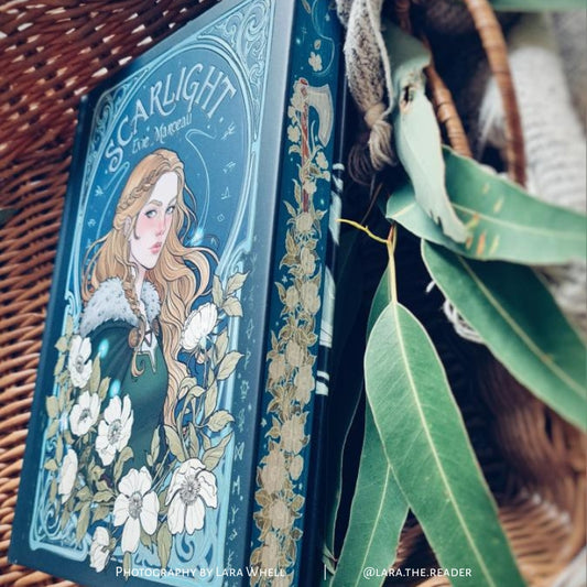 Scarlight special edition hardcover book showing illustrated cover, spine detailing and sprayed edges in styled setting